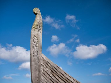 Işık bulutlarıyla dolu güneşli bir günde, Skidbladner 'in pruvası İskoçya' nın Shetland kentindeki Unst adasında Haroldswick yakınlarında sergilenen bir Viking gemisinin tam boyutlu bir kopyası.
