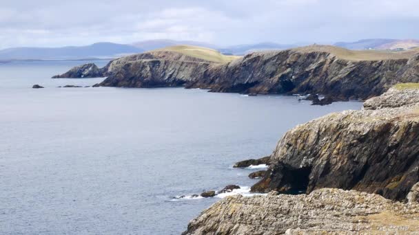 Статический снимок прочных прибрежных скал, составляющих береговую линию Кенны Несс на западной стороне материка, Шетланд, Великобритания. Волны разбиваются о скалы у подножия высоких скал. — стоковое видео