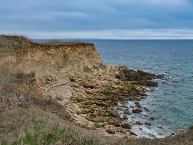 Yıpranmış kireçtaşı uçurumu, Angoulins, Fransa 'da bulutlu bir öğleden sonra Atlantik boyunca aktif kıyı erozyonunu vurguluyor..