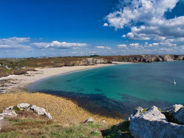 Crozon Yarımadası, Brittany, Fransa 'da Pointe de Pen-Hir yakınlarındaki açık turkuaz bir koy, kumlu bir plaj ve kayalık uçurumların geniş açılı görüntüsü..