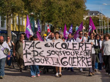 La Rochelle, Fransa - Ekim 02 2025: Protestocular sıcak bir öğleden sonra ışığında Fransa 'nın La Rochelle kentinde düzenlenen siyasi yürüyüş sırasında elde boyanmış bir pankart ve mor bayraklar taşıyorlar.