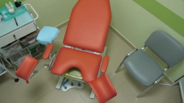 Kontrol paneliyle temiz turuncu jinekolojik muayene koltuğu. Yakın çekim, üst görünüm