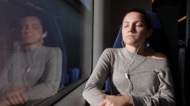 Genç bir kız deniz kenarında bir trende oturuyor. Beyaz kulaklıkla müzik dinler, güneşin tadını çıkarır ve uyur..