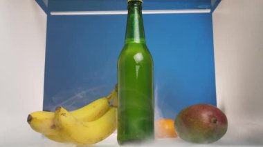 Beyaz adam buzdolabına doğru yürüdü ve bir şişe soğuk bira kaptı. Buzdolabı, raftaki taze meyvelerin üzerine yavaşça yayılan dumanla doludur. Ağır çekimde.