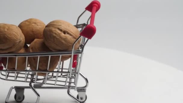 Cestino Supermercato Miniatura Pieno Noci Ruota Lentamente Uno Sfondo Bianco — Video Stock