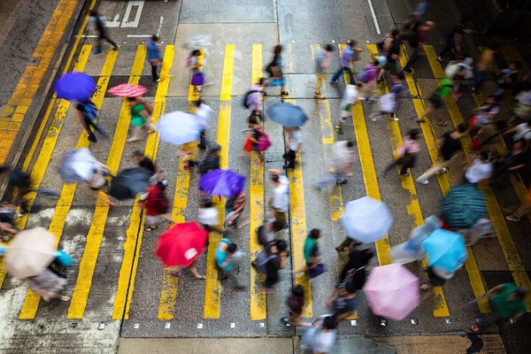 Motion blurred pedestrians crossing Hong Kong street in the rain