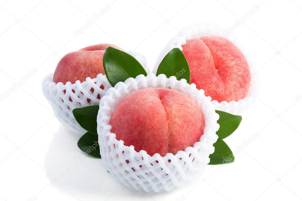 Ripe peach fruits with green leaves isolated on white background