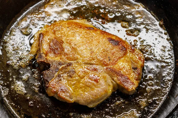 Golden brown pork chop fried in a vintage cast iron skillet