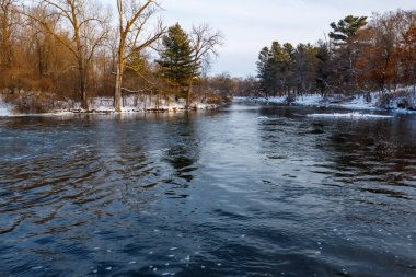 Apple River below the Amery Dam in Amery Wisconsin during winter with snow. Selective focus, background blur and foreground blur.