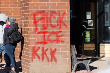 Graffiti spray painted in red reading FUCK ICE KKK on a brick building near the location where Alex Pretti was killed by Border Patrol Agents