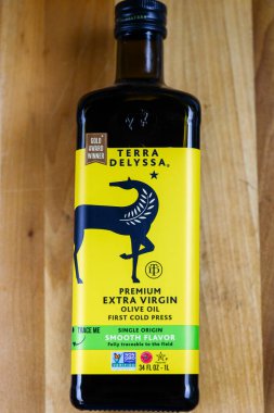 Clear Lake, WI, ABD - 2 Mart 2026: 1 litre Terra Delyssa Premium Ekstra Bakire Zeytinyağı ahşap kesim tahtasında. İlk soğuk basının sarı etiketi, yumuşak aromalı EVOO Tunus 'tan mutfak kullanımı için..