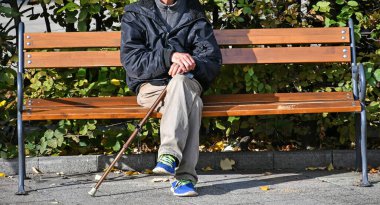 Kıdemli adam bir bankta oturuyor.