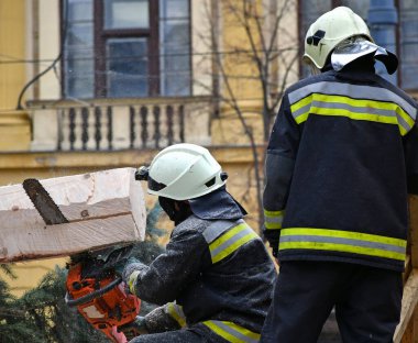İtfaiyeci elektrikli testereyle çam ağacını keser.