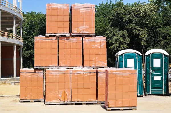 Nieuwe bakstenen en draagbare toiletten op de bouwplaats — Stockfoto