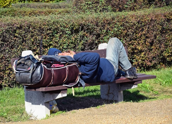 Un vagabundo duerme en un banco. — Foto de Stock
