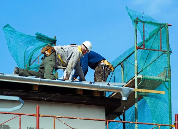 Dakdekkers werken op de bovenkant van een gebouw — Stockfoto