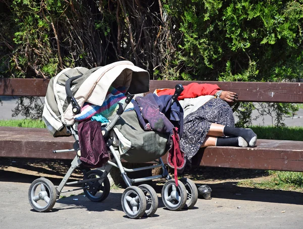 Mulher sem-teto está dormindo em um banco de parque — Fotografia de Stock