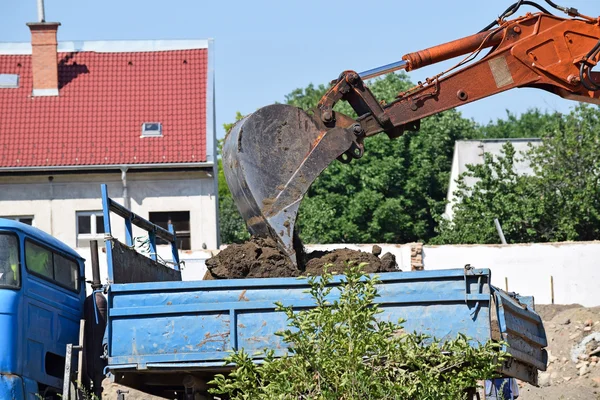 Excavadora está cargando un camión en la construcción de la carretera — Foto de Stock