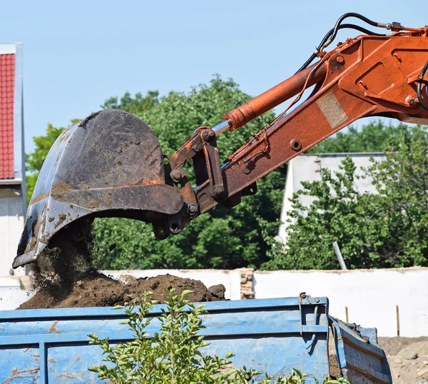 Grävmaskin laddar en lastbil på väg konstruktionen — Stockfoto