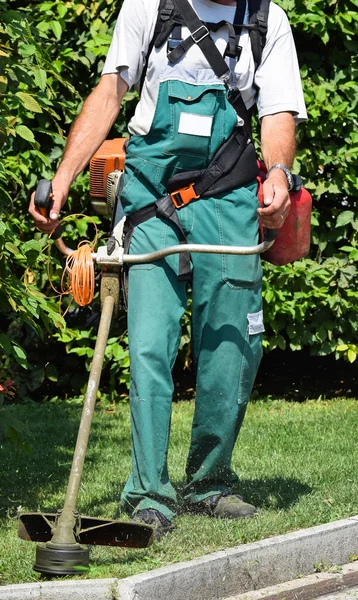 O homem está a cortar a relva no parque — Fotografia de Stock