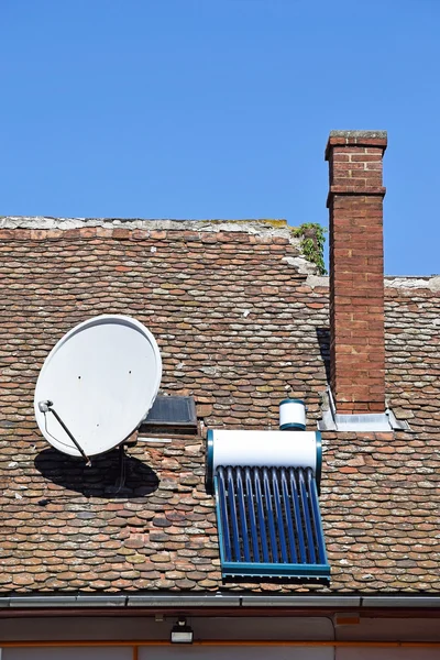 Çatıda güneş ısıtıcı ve uydu çanağı — Stok fotoğraf