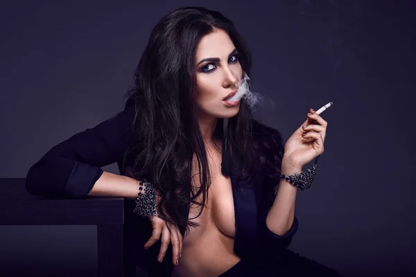 Κομψό καυτή μελαχρινή γυναίκα που καπνίζει ένα τσιγάρο — Φωτογραφία Αρχείου