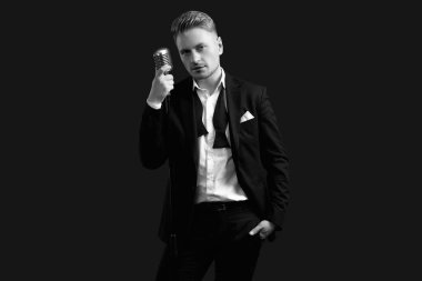 Siyah stüdyo arka planında klasik mikrofonla poz veren zarif smokinli ve papyonlu yakışıklı sarışın adam portresi