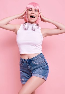 Pembe saçlı, parlak, seksi hippi kızın portresi renkli arka planda kulaklıkla müzik dinlemekten hoşlanıyor.