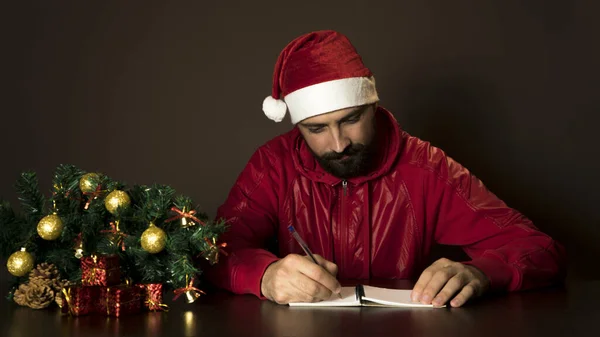 Mladý Moderní Santa Claus Sedí Stolu Stromu Emocionální Portrét Vánoce — Stock fotografie