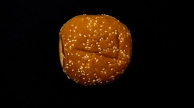 Farklı malzemelerden hamburger yapma süreci. Hareket animasyonunu durdur. Üst Manzara. Domates, soğan, marul yaprağı, sos, pirzola, salatalık, peynir.