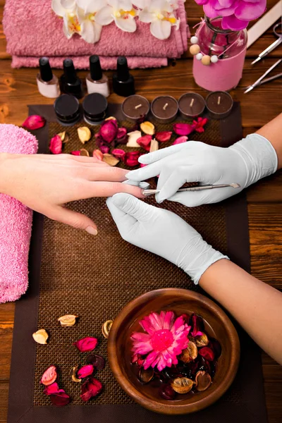 Closeup finger nail care by manicure specialist in beauty salon.