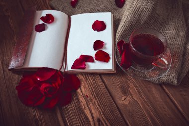 Kompozisyon oluşur gül, hibiscus çay Kupası ve not defteri bir ahşap yüzeye