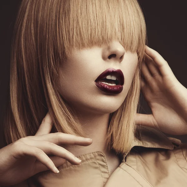 Beautiful blonde woman in a bright coat and dark lips, showing d — Stock Photo, Image