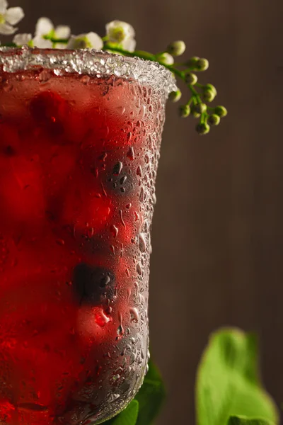 Refresco de bayas con hielo sobre un fondo de madera y flores — Foto de Stock