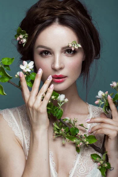 Hermosa chica morena en lencería con un suave maquillaje romántico, labios rosados, sosteniendo flores. La belleza de la cara . — Foto de Stock