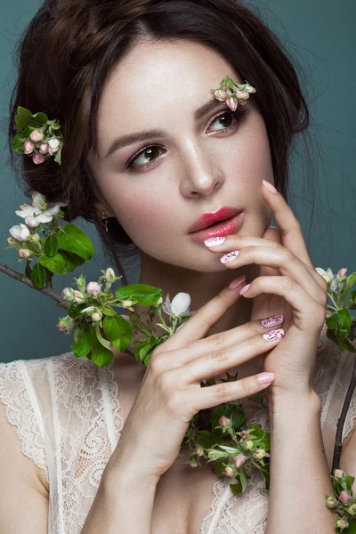 Gyönyörű barna lány fehérnemű-egy gyengéd, romantikus make-up, rózsaszín ajkak gazdaság virágok. Az arc a szépség. — Stock Fotó