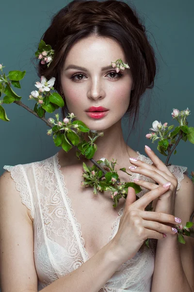 Gyönyörű barna lány fehérnemű-egy gyengéd, romantikus make-up, rózsaszín ajkak gazdaság virágok. Az arc a szépség. — Stock Fotó