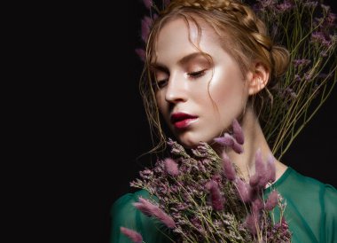 Hafif bir makyaj, saç örgü, kuru çiçekler, yeşil elbise şeklinde güzel kızla. Güzellik.