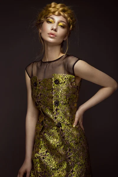 Beautiful girl in a gold dress with creative makeup and braids on her head. The beauty of the face. — Stock Photo, Image