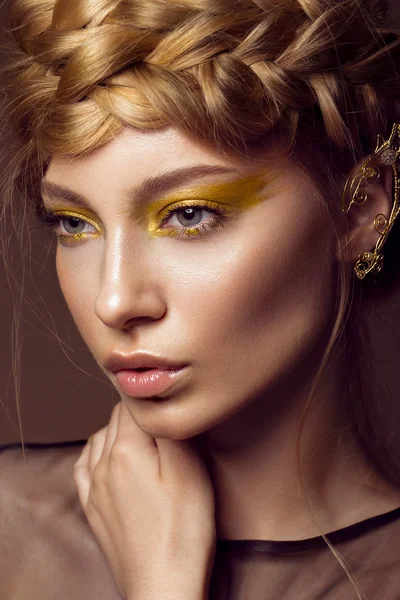 Beautiful girl in a gold dress with creative makeup and braids on her head. The beauty of the face. — Stock Photo, Image