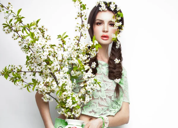 Bella ragazza bruna in abito estivo verde con un delicato trucco romantico, labbra rosa, tenendo i fiori. La bellezza del viso . — Foto Stock