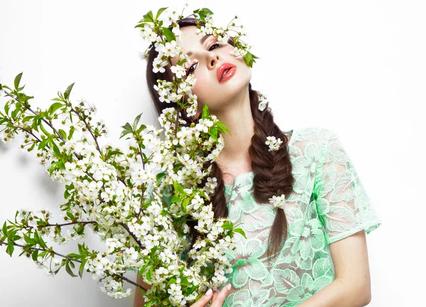 Menina morena bonita em vestido de verão verde com uma maquiagem romântica suave, lábios cor de rosa, segurando flores. A beleza do rosto . — Fotografia de Stock