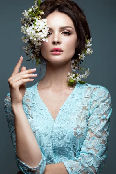 Nazik romantik makyaj ile mavi elbiseli güzel esmer kız pembe dudaklar ve çiçekler. Yüz güzelliği.