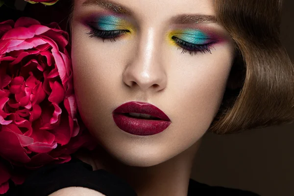 Mooi meisje met kleurrijke make-up, bloemen, retro kapsel. schoonheid gezicht. — Stockfoto