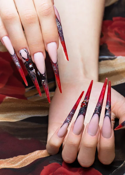 Длинный красивый маникюр на пальцах в черном и красном цветах с пауком. Дизайн ногтей. Крупный план — стоковое фото