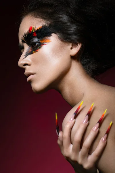 Hermosa chica en imagen de ave Fénix con maquillaje creativo y uñas largas. Diseño de manicura. cara de belleza . — Foto de Stock