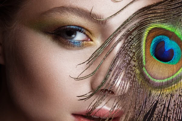 Krásná dívka s zářivě barevný make-up a paví peří na její tváři. Krása. Detail — Stock fotografie