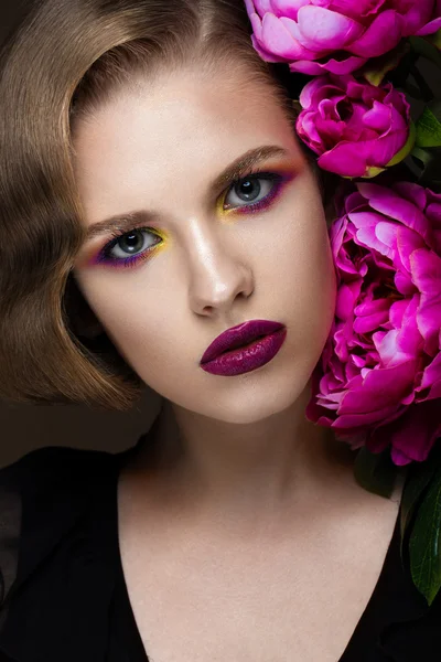 Schönes Mädchen mit buntem Make-up, Blumen, Retro-Frisur. Schönheit Gesicht. — Stockfoto