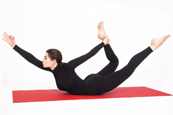 Menina atlética bonita em um terno preto fazendo ioga. Naukasana asana barco pose. Isolado sobre fundo branco . — Fotografia de Stock