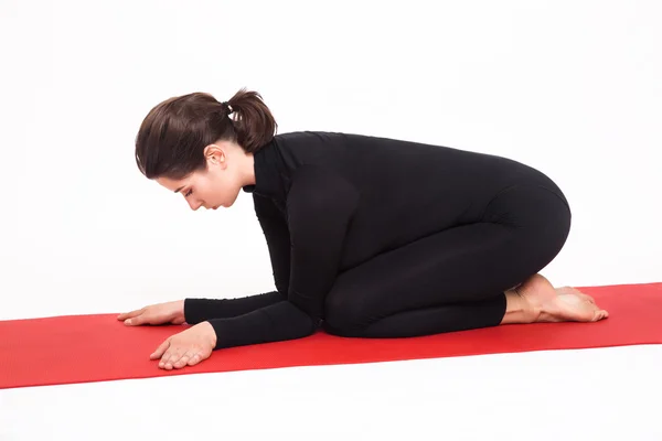 Beautiful athletic girl in black suit doing yoga. karenukasana asana - pose lying elephant. — Stock Photo, Image